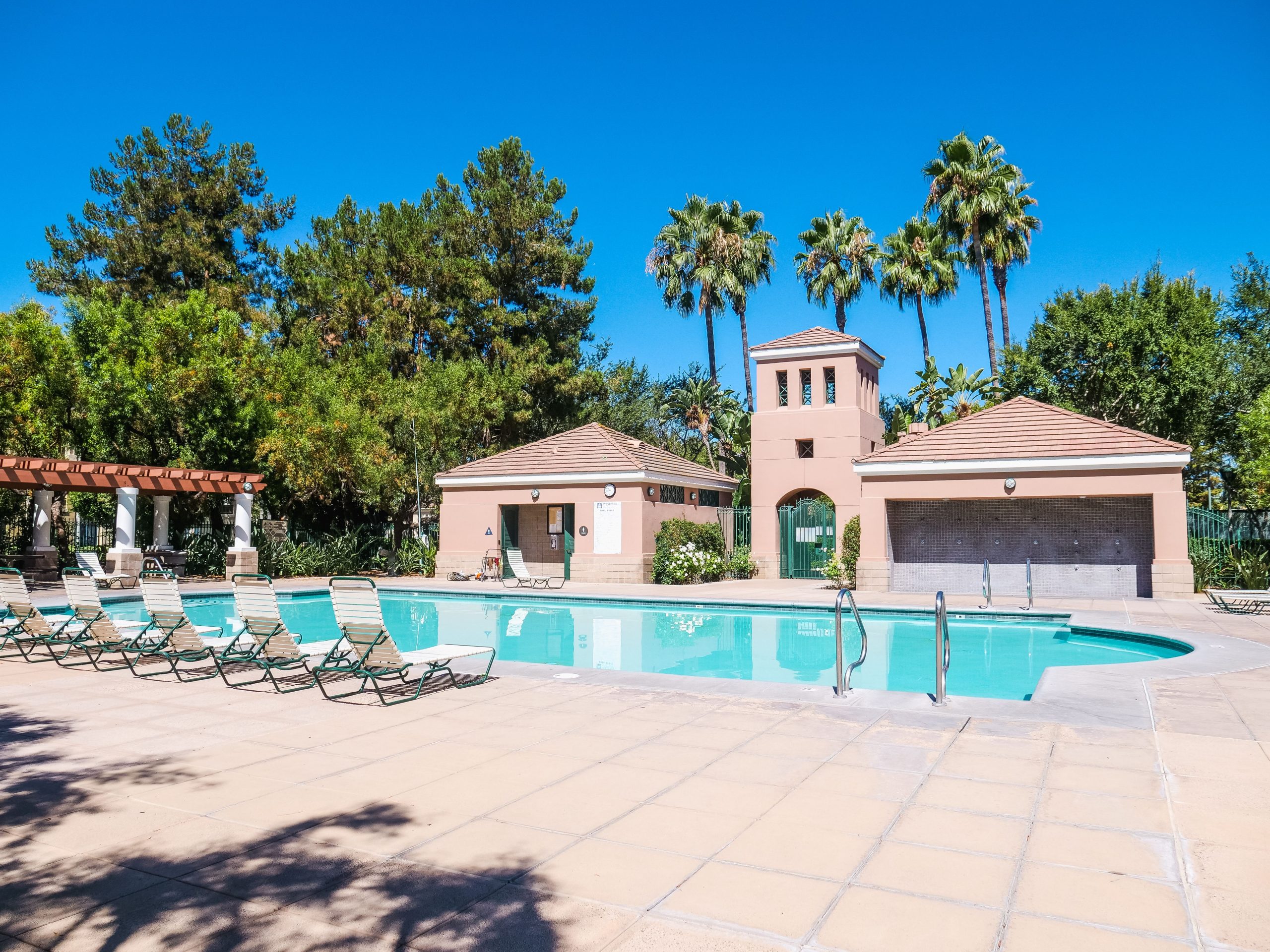 A serene poolside setting with sun loungers under a vibrant blue sky, perfect for relaxation.